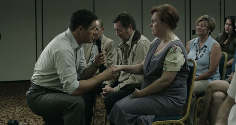 A Crooked Somebody 2017 Movie Scene Rich Sommer as Michael Vaughn holding a woman's hand while communicating with her deceased daughter