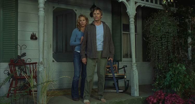 A History of Violence 2005 Movie Scene Viggo Mortensen as Tom Stall holding a shotgun in front of his house with Maria Bello as Edie standing next to him