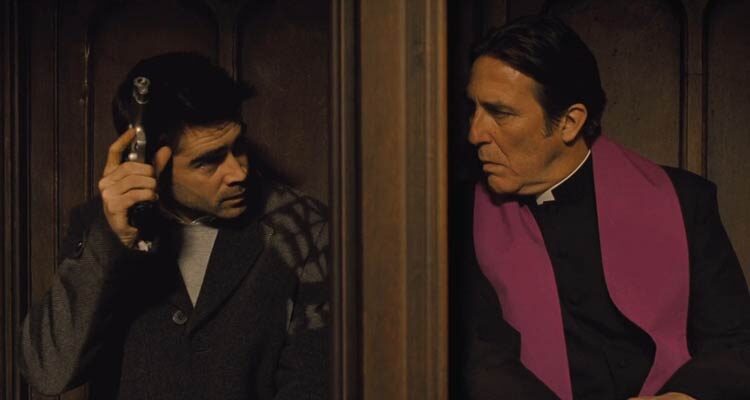 In Bruges 2008 Movie Scene Colin Farrell as Ray holding a gun in a confessional booth next to Ciarán Hinds as Priest