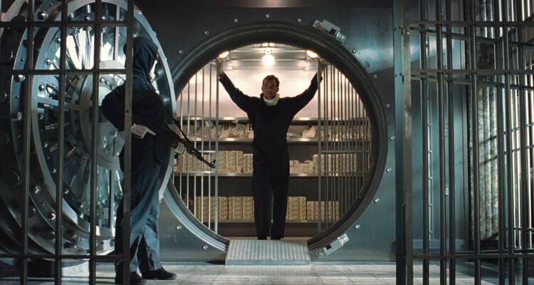 Inside Man 2006 Movie Scene Clive Owen as Dalton Russell standing inside the vault of the bank he's robbing with one of his helpers outside holding an AK-47