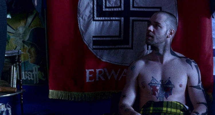 Romper Stomper 1992 Movie Scene Russell Crowe as Hando sitting up in his bed with a giant red flag with a swastika behind him