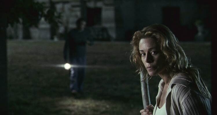 The Orphanage 2007 Movie Scene Belén Rueda as Laura holding a stick and exploring the courtyard at night after she heard a sound