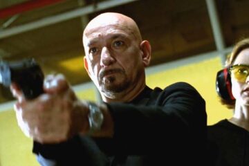 You Kill Me 2007 Movie Scene Ben Kingsley as Frank Falenczyk holding a gun in a gun range with Téa Leoni as Laurel standing behind him