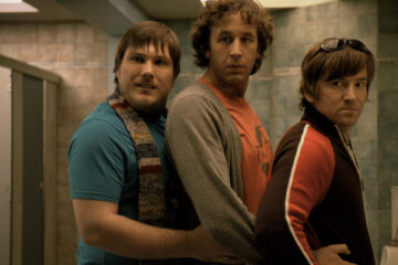 Frequently Asked Questions About Time Travel 2009 Movie Scene Chris O'Dowd as Ray, Marc Wootton as Toby, and Dean Lennox Kelly as Pete standing next to each other in toilet
