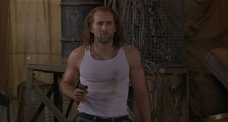 Con Air 1997 Movie Scene Nicolas Cage as Cameron Poe wearing a sleeveless t-shirt and holding a gun showing off his muscular body