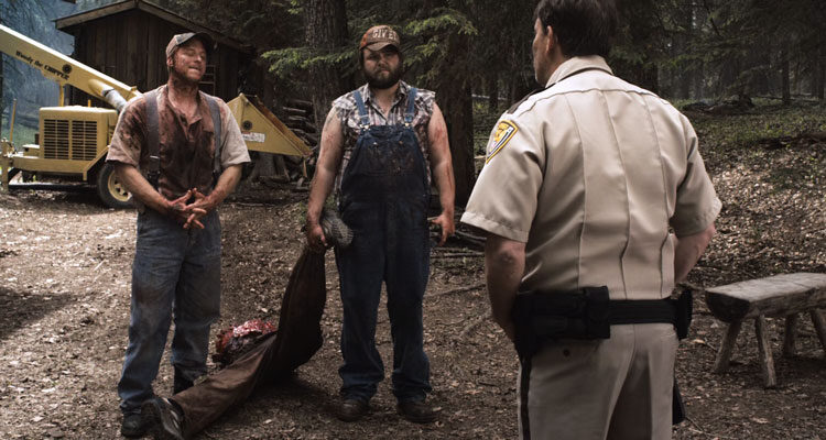 Tucker And Dale Vs Evil 2010 Movie Scene Tyler Labine as Dale and Alan Tudyk as Tucker holding half a human body in front of a sheriff