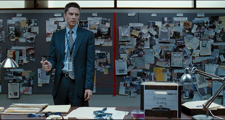 The Double 2011 Movie Scene Topher Grace as Ben Geary in front of the wall covered with clues trying to figure out who the assassin is