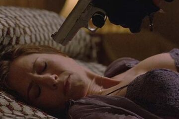 Derailed 2005 Movie Scene Jennifer Aniston as Lucinda Harris laying in bed in lingerie with a gun to her head held by Vincent Cassel as LaRoche