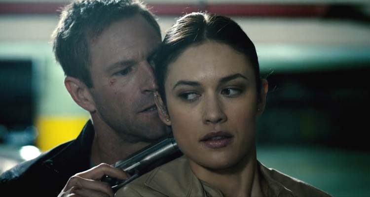 Erased 2012 Movie Scene Aaron Eckhart as Ben Logan holding a gun to Olga Kurylenko as Anna Brandt's head