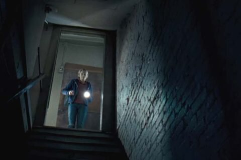The Innkeepers 2011 Movie Scene Sara Paxton as Claire using a flashlight to look into the basement after hearing strange noises