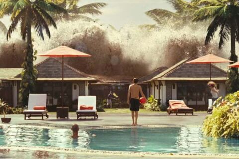 The Impossible 2012 Movie Scene A small boy holding a red ball next to a pool looking at an incoming tsunami wave hitting the resort