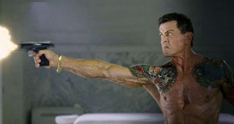 Bullet to the Head 2012 Movie Scene Sylvester Stallone as James Bonomo firing a gun with his tattoos showing