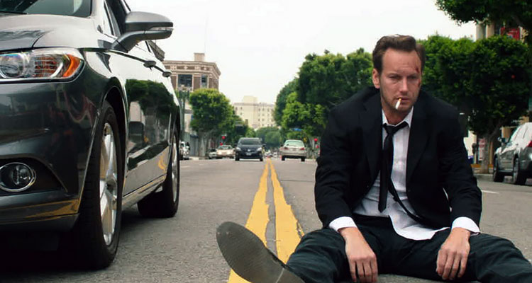 Stretch 2014 Movie Scene Patrick Wilson as Stretch sitting on the road and smoking a cigarette