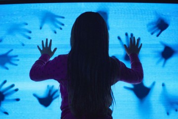 Poltergeist 2015 Movie Scene Kennedi Clements as Madison Bowen holding her hands on the television set