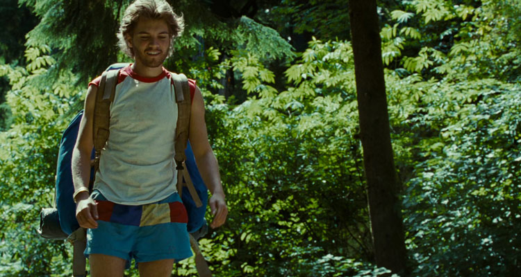 Into The Wild 2007 Movie Image Emile Hirsch as Chris McCandless in a shirt and shorts walking through the forest