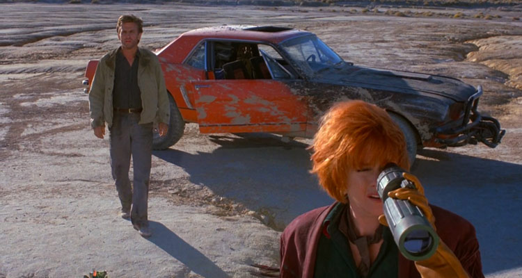 Cherry 2000 1987 Movie David Andrews as Sam Treadwell walking away from the red car and towards Melanie Griffith as E. Johnson looking through the special binoculars