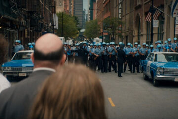 The Trial of the Chicago 7 2020 Movie Police forces lining up in front of the police station where Eddie Redmayne as Tom Hayden is being held