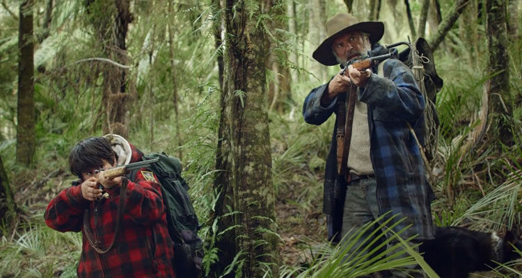 Hunt For The Wilderpeople 2016 Movie Sam Neill and Julian Dennison holding guns in the jungle