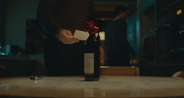 The Gift 2015 Movie Bottle of wine Gordo left as a present on a table with Jason Bateman reading the note