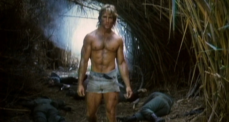 Deadly Prey 1987 Movie Scene Ted Prior as Mike Danton in cutoff jeans shorts showing his muscles as he walks over dead bodies
