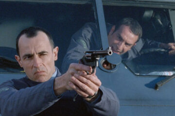 Le Convoyeur AKA Cash Truck 2004 Movie Scene Albert Dupontel as Alexandre Demarre holding a gun in front of the armored car with Jean Dujardin as Jacques