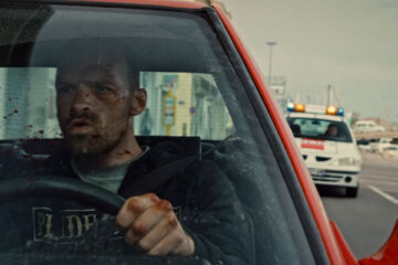 Lost Bullet 2020 Movie Scene Alban Lenoir as Lino driving a red Renault 21 with the police behind him