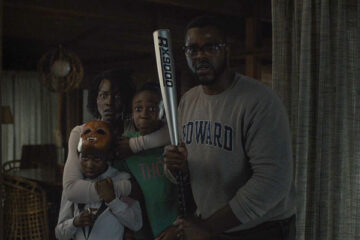 Us 2019 Movie Scene Winston Duke holding a baseball bat with the rest of the family behind him as they first see the strangers