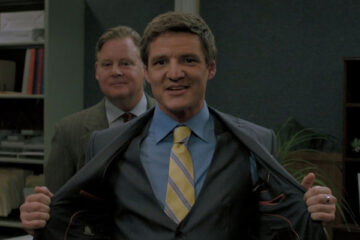 Bloodsucking Bastards 2015 Movie Scene Pedro Pascal as Max in a suit smiling with Joel Murray as Ted behind him