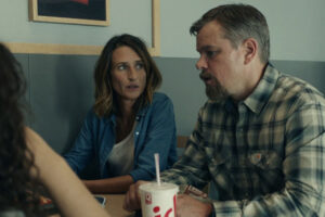 Stillwater 2021 Movie Scene Matt Damon as Bill Baker and Camille Cottin as Virginie talking to two girls in a cafe