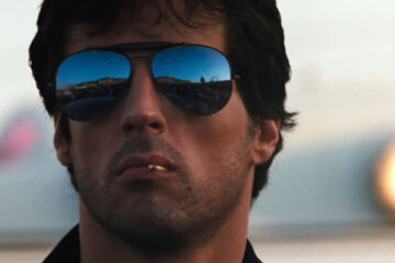 Cobra 1986 Movie Scene Sylvester Stallone as Marion Cobretti wearing sunglasses and playing with a matchstick in the corner of his mouth