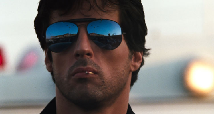 Cobra 1986 Movie Scene Sylvester Stallone as Marion Cobretti wearing sunglasses and playing with a matchstick in the corner of his mouth