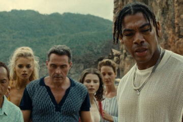 Old 2021 Movie Scene Aaron Pierre as Mid-Sized Sedan, Rufus Sewell as Charles, Ken Leung as Jarin, Abbey Lee as Chrystal, Vicky Krieps as Prisca and Thomasin McKenzie as Maddox looking at a corpse at the beach