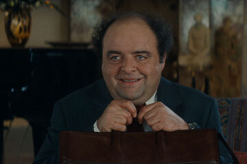 The Dinner Game 1998 Movie Scene Jacques Villeret as François Pignon holding his briefcase and smiling