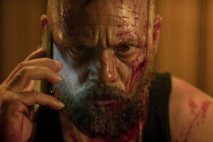 Xtremo AKA Xtreme 2021 Movie Scene Teo García as Max all bloody making a phone call and grunting