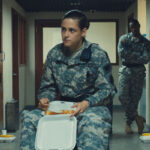 Camp X Ray 2014 Movie Scene Kristen Stewart as Cole in a uniform sitting on a lunch trolley and eating