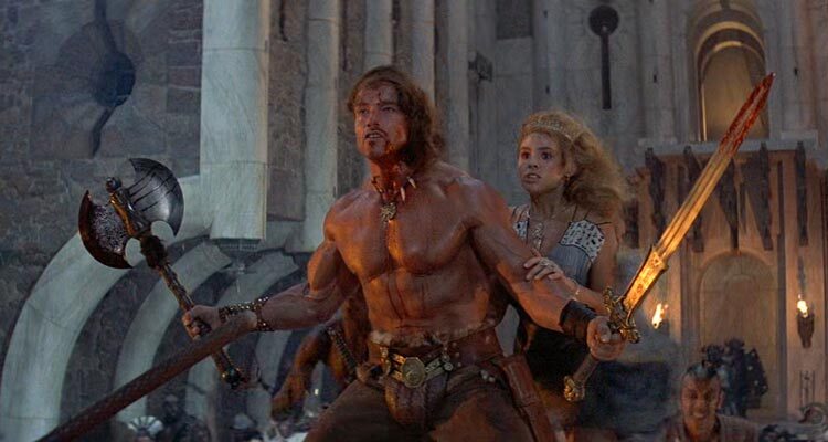 Conan The Destroyer 1984 Movie Scene Arnold Schwarzenegger as Conan holding a sword and an axe protecting Olivia d'Abo as Princess Jehnna