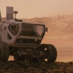 The Last Days On Mars 2013 Movie Scene An astronaut standing next to a huge Mars rover with the storm approaching on the horizon