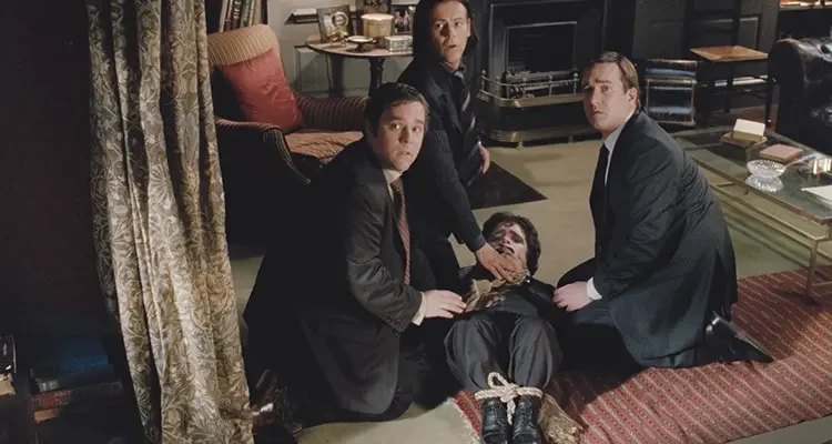 Death At A Funeral 2007 Movie Scene Matthew Macfadyen as Daniel, Andy Nyman as Howard and Rupert Graves as Robert tying up Peter Dinklage as Peter