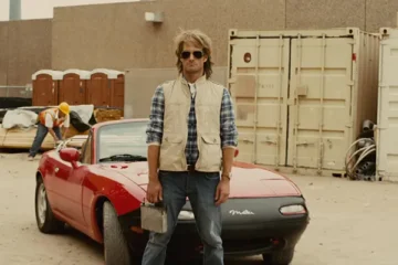 MacGruber 2010 Movie Scene Will Forte as MacGruber holding his car stereo in front of his car, red Mazda Miata