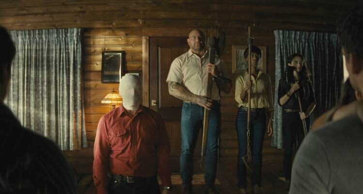 Knock at the Cabin 2023 Movie Scene Dave Bautista as , Leonard, Nikki Amuka-Bird as Sabrina, and Abby Quinn as Adriane holding their weapons as they're preparing to kill Rupert Grint as Redmond