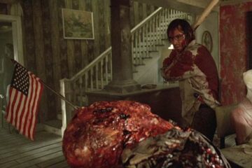 The Hills Have Eyes 2006 Movie Scene Aaron Stanford as Doug bloody and holding bat as he roams the mutant's house and finds a corpse of a man with an American flag stuck in his head