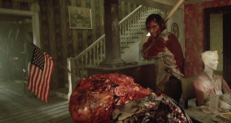 The Hills Have Eyes 2006 Movie Scene Aaron Stanford as Doug bloody and holding bat as he roams the mutant's house and finds a corpse of a man with an American flag stuck in his head