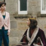 The Lost King 2022 Movie Scene Sally Hawkins as Philippa Langley talking on the phone with Harry Lloyd as Richard III sitting next to her