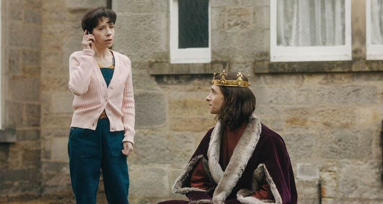 The Lost King 2022 Movie Scene Sally Hawkins as Philippa Langley talking on the phone with Harry Lloyd as Richard III sitting next to her
