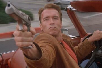 Last Action Hero 1993 Movie Scene Arnold Schwarzenegger as Jack Slater driving a car and shooting his desert eagle gun at the bad guys