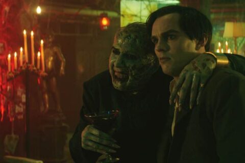Renfield 2023 Movie Scene Nicholas Hoult as Renfield and Nicolas Cage as Dracula talking in his lair while he's drinking blood