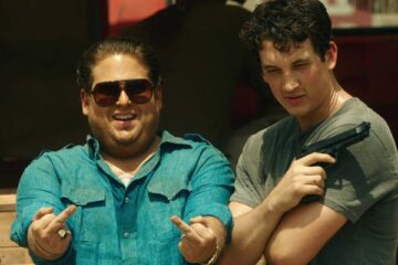 War Dogs 2016 Movie Scene Jonah Hill as Efraim Diveroli and Miles Teller as David Packouz posing for a picture in front of a truck after a successful delivery of weapons