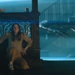 No One Will Save You 2023 Movie Scene Kaitlyn Dever as Brynn hiding from the aliens in her house while they use a tractor beam to collect the one she killed