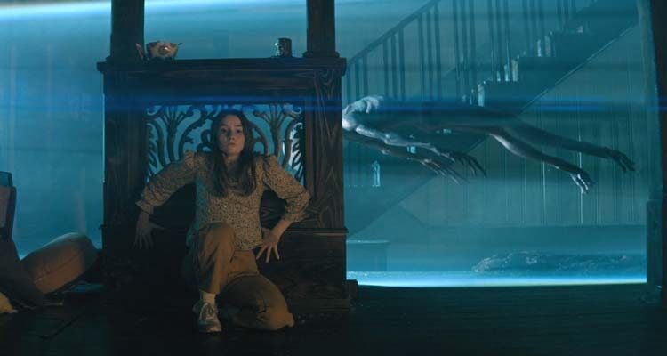 No One Will Save You 2023 Movie Scene Kaitlyn Dever as Brynn hiding from the aliens in her house while they use a tractor beam to collect the one she killed