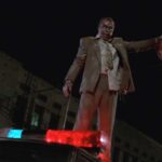 Tales From The Hood 1995 Movie Scene Tom Wright as Zombie Martin Moorehouse holding the severed head of Wings Hauser as Strom and standing on top of a police car